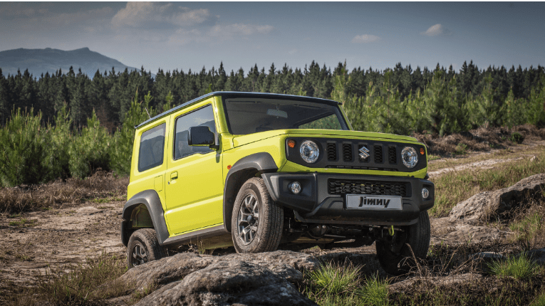 Green Suzuki Jimny standing on mountain rocks