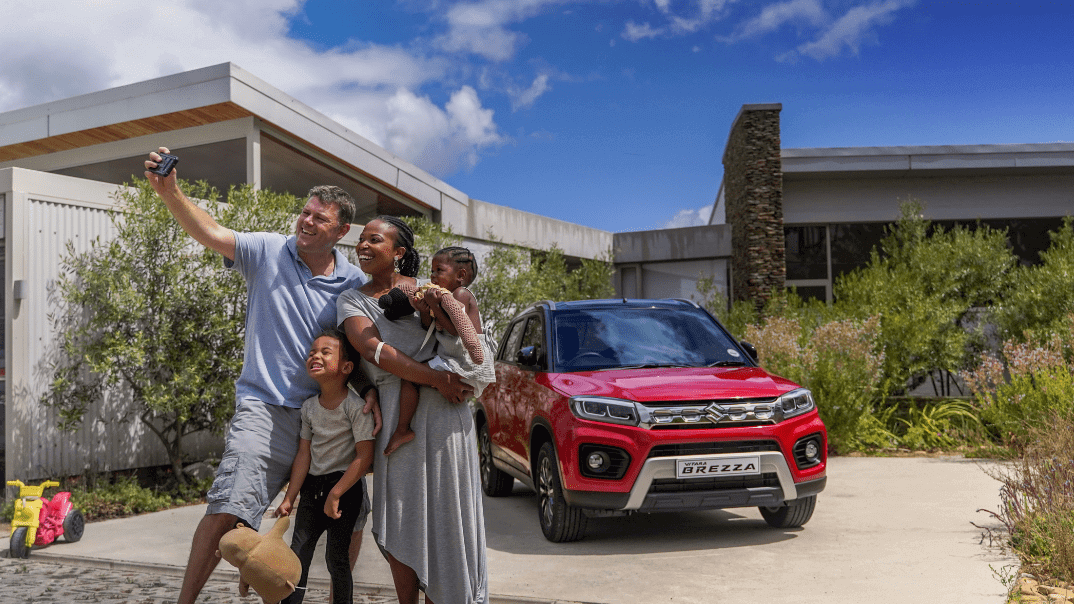 Family taking a picture infront of a Red Suzuki Vitara Brezza