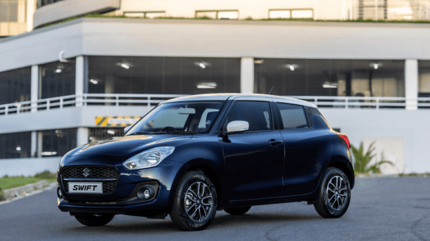 Black suzuki swift parked on a tar road next to a building