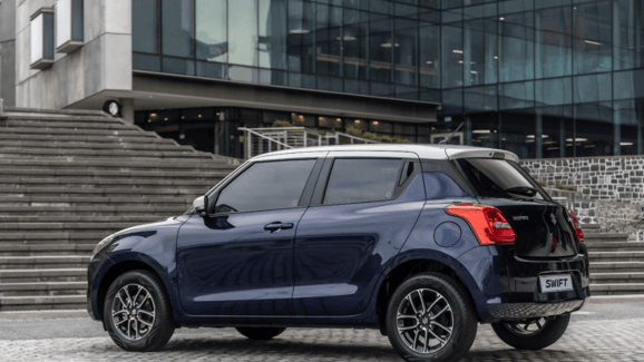 blue suzuki swift parked in front of stairs