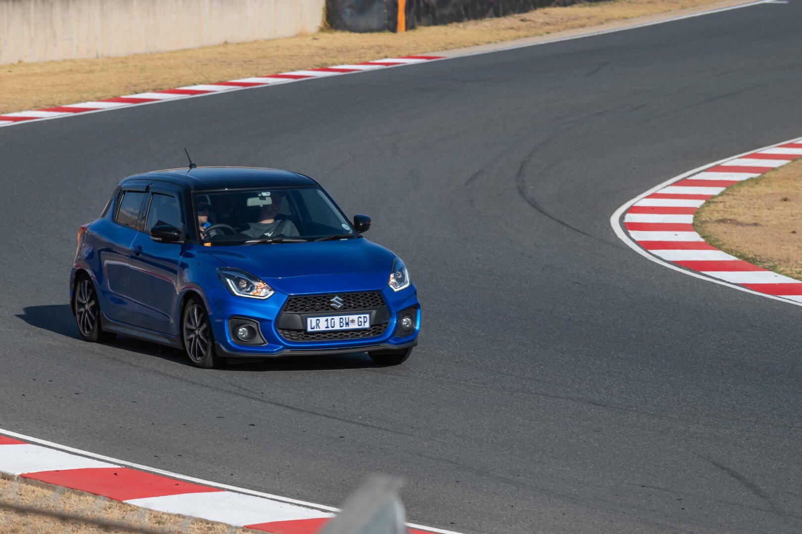 Blue Suzuki Swift in front on the track 