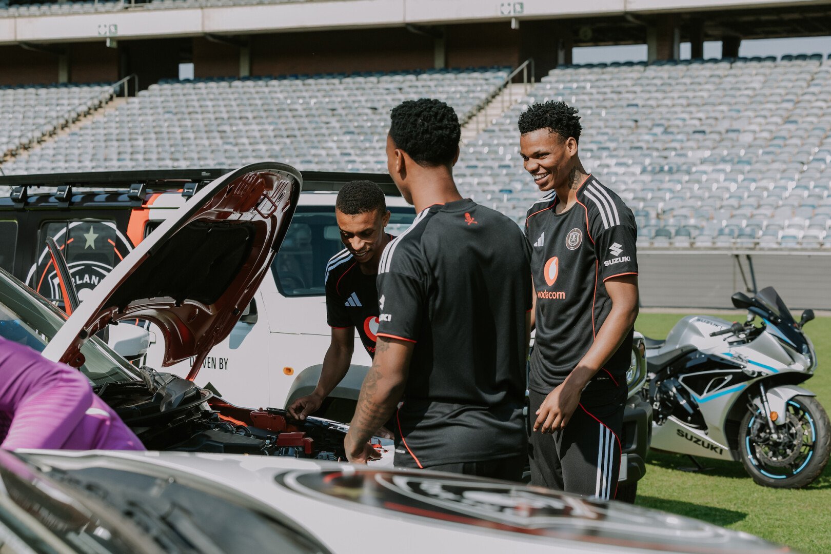 Orlando Pirates Players in front of an open Suzuki bonnet 